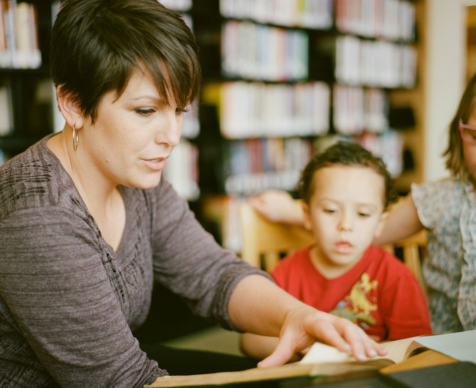 Lead editor reading with a young student in a library setting.